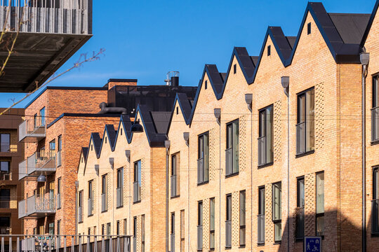 Contemporary brick housing in Ørestad, Copenhagen with geometric roofline and shadow play, architectural design and real estate concept for business visuals