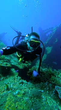 A male scuba diver explores underwater coral reef near USAT Liberty wreck, Bali