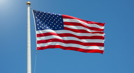 Fototapeta premium American flag billowing proudly in a clear blue sky.