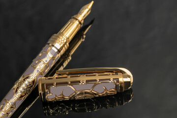 Naklejka premium Fountain pen on gold color on marble gray background. Stationery.
