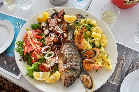 Greek Grilled Seafood Platter with Vegetables and Potatoes in Restaurant Setting