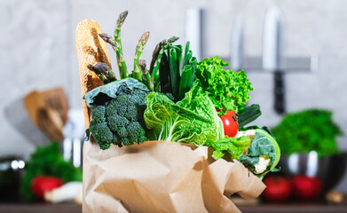 Paper bag filled with freshly harvested vegetables and greens - healthy cooking ingredients