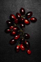 Fresh organic black tomatoes on dark background, ready for healthy food preparation in the kitchen