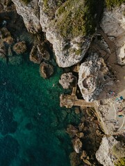 Aerial view of rocky coastline and sunbathers.