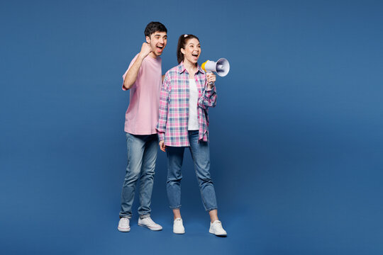 Fototapeta Full body young winner couple two friends family man woman wear pink casual clothes together scream in megaphone announces discounts sale Hurry up isolated on plain blue background. Lifestyle concept.
