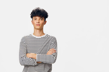 portrait of young man in striped shirt with crossed arms against white background, standing...