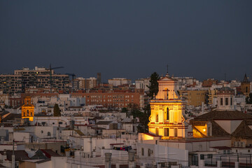 A view of a prominant church, set amoungst the buildings of Seville, Andalusai, Spain, lit up at night
