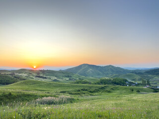 Fototapeta premium Buzău Green Hills Sunset. A serene landscape view captures rolling green hills in Buzău County, Romania, bathed in the warm hues of a sunset. 