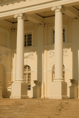 Close-up of a neoclassical palace facade with tall white columns, arched windows, and ornate stucco decorations.