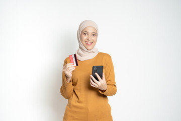 Confident woman holding a credit card and smartphone, expressing satisfaction and readiness for online activities such as shopping or banking.