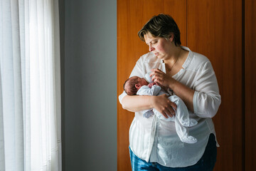 Mother bottle feeding newborn son at home