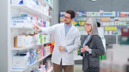 Male pharmacist advising medicine to female client. Man druggist advising pills to woman customer....
