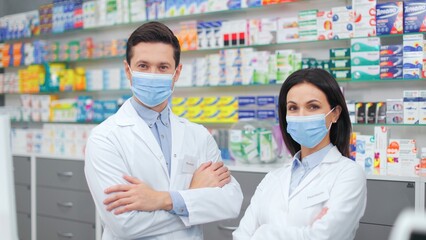 Pharmacists carying out audits of medicines. Two druggists in uniform standing near showcase with...