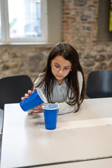 A girl wearing glasses and a sweatshirt plays active board games in the school cafeteria. Educational concept of children's activity and play