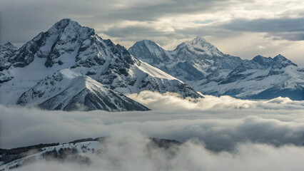Naklejka premium Majestic Snow-Capped Mountains Rising Above a Sea of Clouds