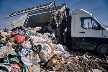 A truck unloads garbage at a landfill: piles of bags, plastic, and boxes form a heap of waste.