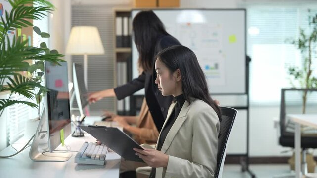 Project manager guiding employee through spreadsheet data