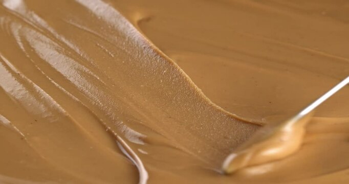 Knife stirs peanut butter, close-up of the peanut butter texture.