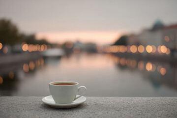 serene coffee cup on waterfront reflecting sunset in water
