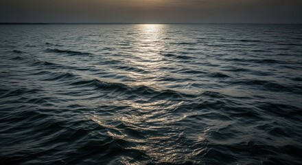A view of the ocean with sunlight reflecting on the water surface and horizon in the distance at sunset