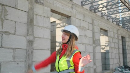 On a construction site, a young designer wearing earbuds enjoys a brief musical break. Smiling and carefree, she breaks into an energetic dance, momentarily forgetting the blueprints and calculations.