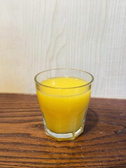 Glass of orange juice on wooden table.