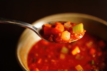 A spoonful of delicious vegetable soup with colorful vegetables.