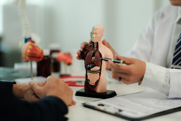 A doctor points to the chest area while explaining treatment options to a patient experiencing...