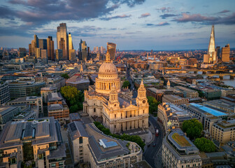 Aerial summer sunset view of the skyline of London, England, with St. Pauls Cathedral, city skyscrapers and river Thames with golden sunlight