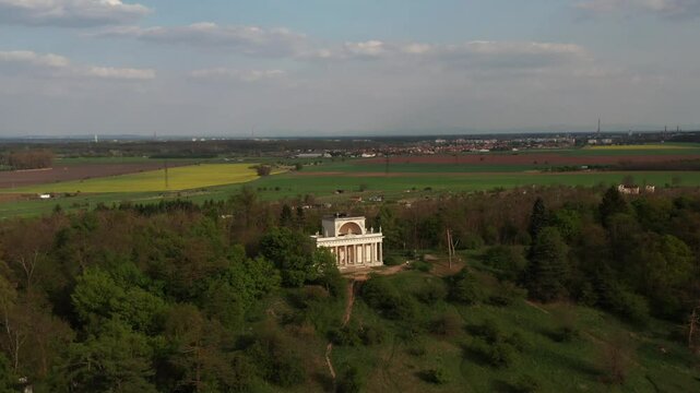 Aerial orbiting view of Apollo Temple in Lednice, Czechia, standing beside a calm lake