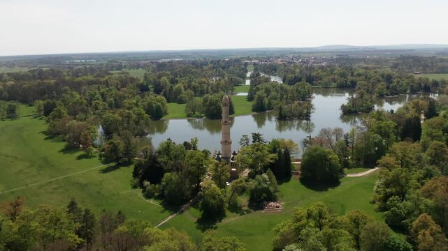 Aerial orbiting view of the Lednice minaret in Czechia, rising elegantly above blooming spring trees