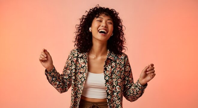 Happy young woman with curly hair dancing and wearing earbuds