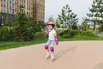 A little curly-haired girl rollerskates within the necessary facilities in the city. In a helmet...