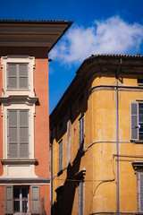 Old orange and yellow facades with closed shutters in historic district of Reggio Emilia 