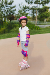 A little curly-haired girl rollerskates within the necessary facilities in the city. In a helmet and armbands