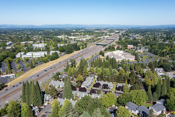 Aerial drone picture of US-26 highway, and a beautiful residential apartment complex in Cedar Mill, Portland, OR, captured at morning. Green courtyards, housing buildings are visible	

