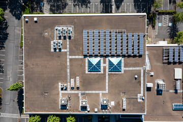 Aerial drone picture of a modern commercial building in Cedar Mill, Portland, OR, showcasing rooftop solar panels, HVAC units and large empty parking lot, promoting clean energy and sustainability	

