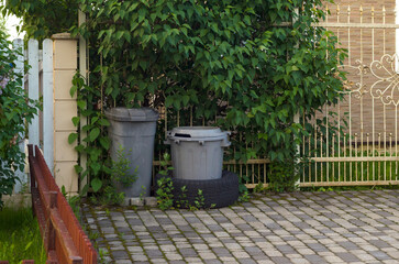 Naklejka premium Two garbage bins at fence.Periodic garbage collection.