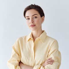 Woman poses confidently with arms crossed against white background. Self-assured and modern style, expressing strength.