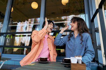 Joyful multicultural friends share a moment of bliss at a cafe in the afternoon sunlight