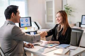 A man shakes hands with a woman in a business setting