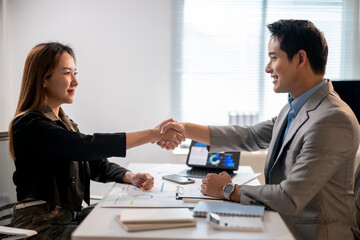 A man shakes hands with a woman in a business meeting