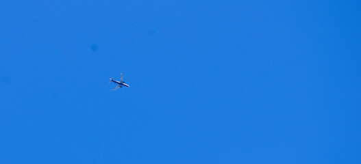 The passenger airplane is flying far away in blue sky.