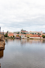 Obraz premium A picturesque view of Prague Castle and surrounding historical architecture, with reflections on the Vltava River under a cloudy sky