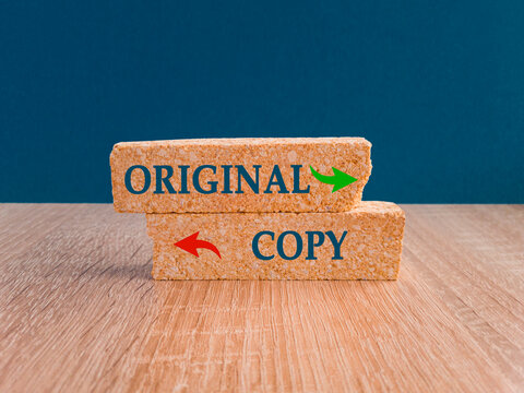 Words Original or copy on brick blocks with two arrows. Beautiful blue background. Wooden table. Symbol of Original copycat originality cheap and bad copy or unique top quality product guaranteed
