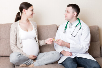Doctor is giving pills to a pregnant woman and explaining how to use them. Treatment during pregnancy