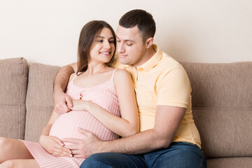 Happy pregnant woman and her husband waiting for baby at the home. happy family love and care concept