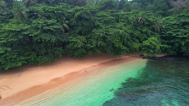 Aerial backwards view from the transparant sea of Margarida beach with a boat anchored at se beach. Ilha do Principe (Prince Island),Africa
