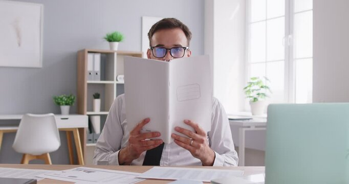 Accountant enjoys a break from work in office by playing with pencils. Surrounded by documents, he finds a funny way to pass the leisure time, adding some fun to workday and lightening the boredom.