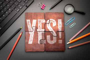 Positive Affirmation Concept with Assembled Puzzle Spelling YES Surrounded by Office Supplies